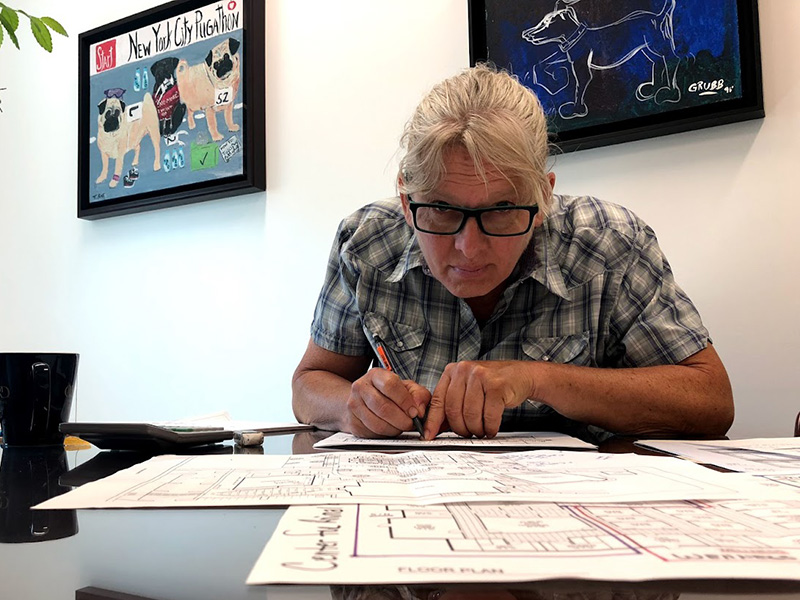 Dr. Wagner sitting at a desk marking up a shelter's floor plan with a pen.